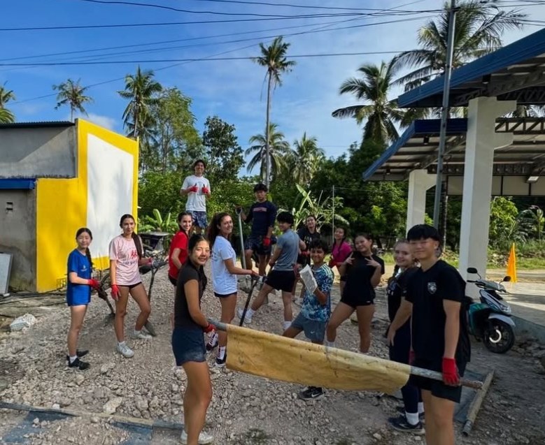 Students carrying building materials through the village